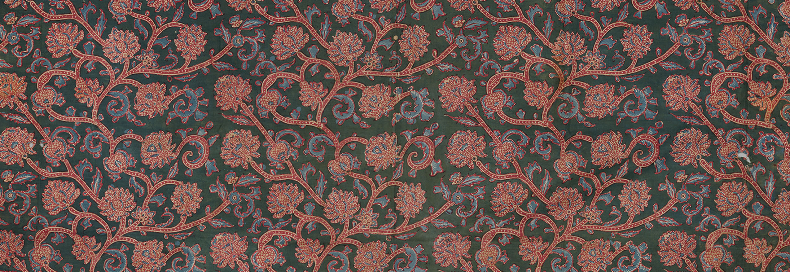 A block-printed textile with a floral and vine pattern on a dark-coloured ground.